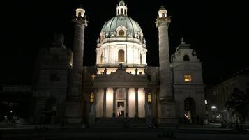 A grand building with a large dome and two tall columns, illuminated at night.
