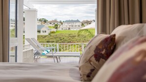 A bedroom with a balcony overlooking a residential area. - Modern house, solar-heated pool & stunning views, at Kingswood Golf Resort (George)