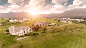 A large, modern house with a spacious lawn and a view of the surrounding landscape. - Modern house, solar-heated pool & stunning views, at Kingswood Golf Resort (George)