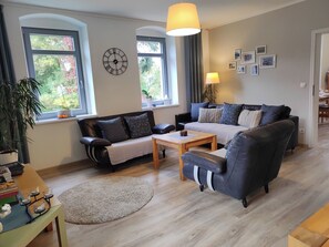 A living room with a sofa, a coffee table, and a dining area with a table and chairs.