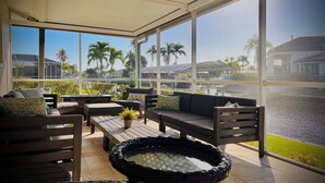 A sunlit patio with a view of a marina, featuring a sofa, a small table, and a decorative bowl.