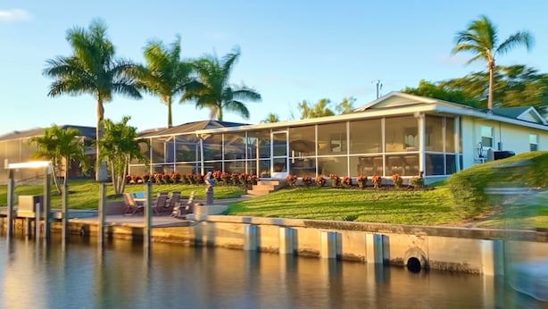 A modern building with a glass facade, a pool, and palm trees.