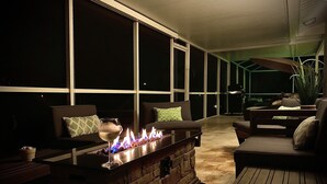 A patio area with a fire feature, seating, and large windows.