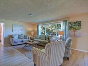 Relax in this stylish living room with a sofa set, coffee table, and armchairs, offering a view of the outdoors.