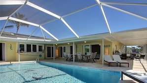 A covered swimming pool with lounge chairs and a patio area.