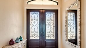 A dark wooden double door with decorative glass panels and a white-framed mirror on the wall. - SW Cape Coral Waterfront Villa "Summerset" | Pool + Jacuzzi | south-facing | (Cape Coral)