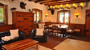 A cozy room with a wooden dining table, leather sofa, and a large cabinet.