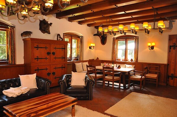 A cozy room with a wooden dining table, leather sofa, and a large cabinet.