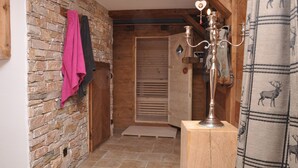 A narrow hallway with a stone wall, wooden door, and a metal candelabra.