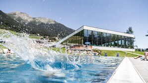 En swimmingpool med kig til en moderne bygning med store vinduer og en glasfacade.
