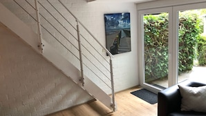 A staircase with a metal railing, a door leading to a garden, and a framed picture on the wall. - Corner house 3 bedrooms on the Grevelingen Sea in the park Aquadelta, free Wi-Fi (Bruinisse)