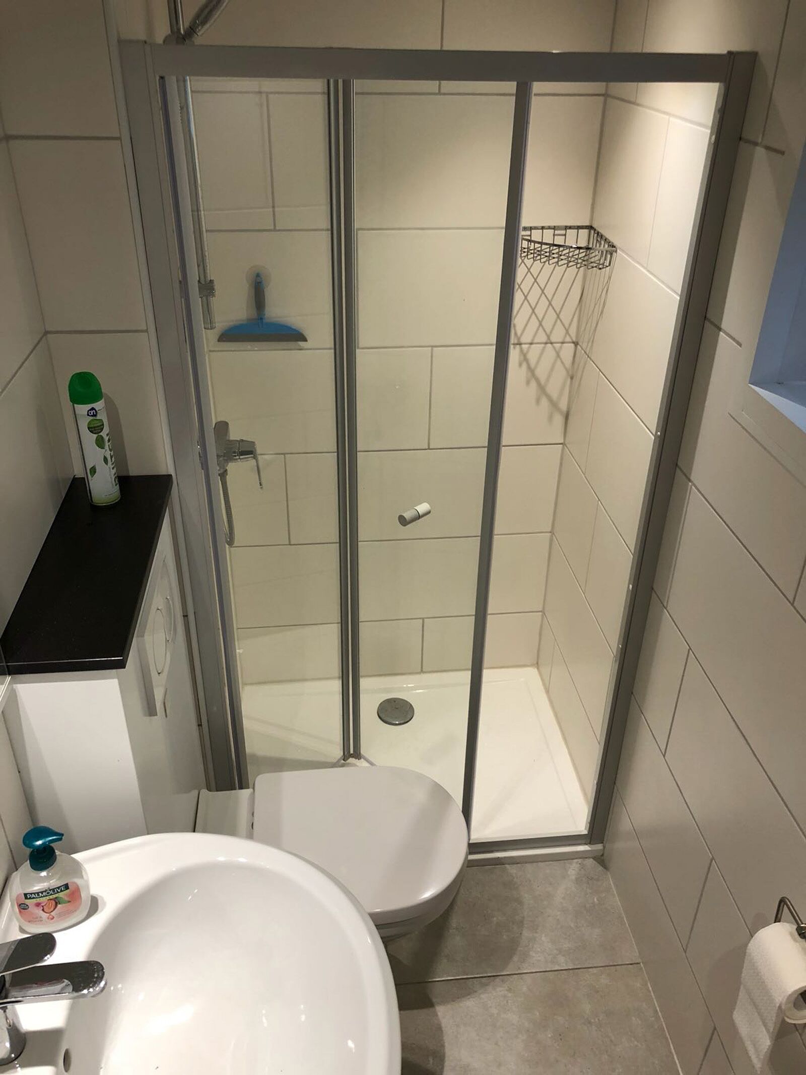 Ein kleines Badezimmer mit Dusche, Toilette und Waschbecken.