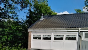 A covered patio with a table and chairs, a fenced backyard, and a house with a tiled roof. - Corner house 3 bedrooms on the Grevelingen Sea in the park Aquadelta, free Wi-Fi (Bruinisse)