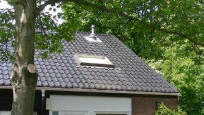 A two-story house with a dark tiled roof, a white door, and a small window. - Corner house 3 bedrooms on the Grevelingen Sea in the park Aquadelta, free Wi-Fi (Bruinisse)