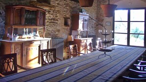 Un interior rústico con paredes de piedra, muebles de madera y un amplio ventanal que deja entrar luz natural.