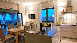 Ein modernes Hotelzimmer mit Essbereich, einer Küche und einem großen Fenster mit Blick.