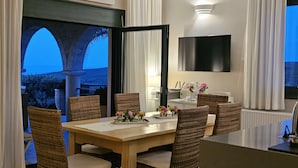Ein Essbereich mit Holztisch, Korbstühlen und Blick ins Freie.