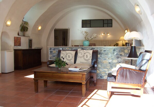 A cozy living room with a stone wall, wooden furniture, and a tiled floor. - Stylish apartment with a beautiful garden, 5 km to the beach (Dolcedo)