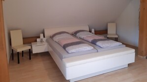 A bedroom with a large bed, two bedside tables, and a chair. - Apartment at St. James, amidst the nature park Südeifel, on the edge of Islek (Lascheid)
