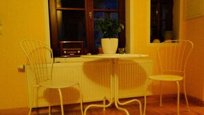 Ein Zimmer mit Heizkörper, Blumentopf und zwei weißen Stühlen um einen kleinen Tisch.