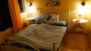 Ein Bett mit Metallgestell, zwei Nachttische und ein kleiner runder Tisch.
