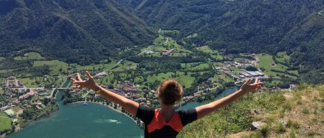 Une personne se tient sur une colline, d’où elle a une vue sur une vallée, un lac et des bâtiments.