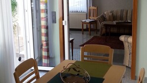 Un espace repas comprenant une table, des chaises et donnant sur un salon.