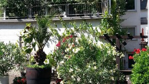 Un immeuble de deux étages doté de balcons, de plantes en pot et d’un drapeau.