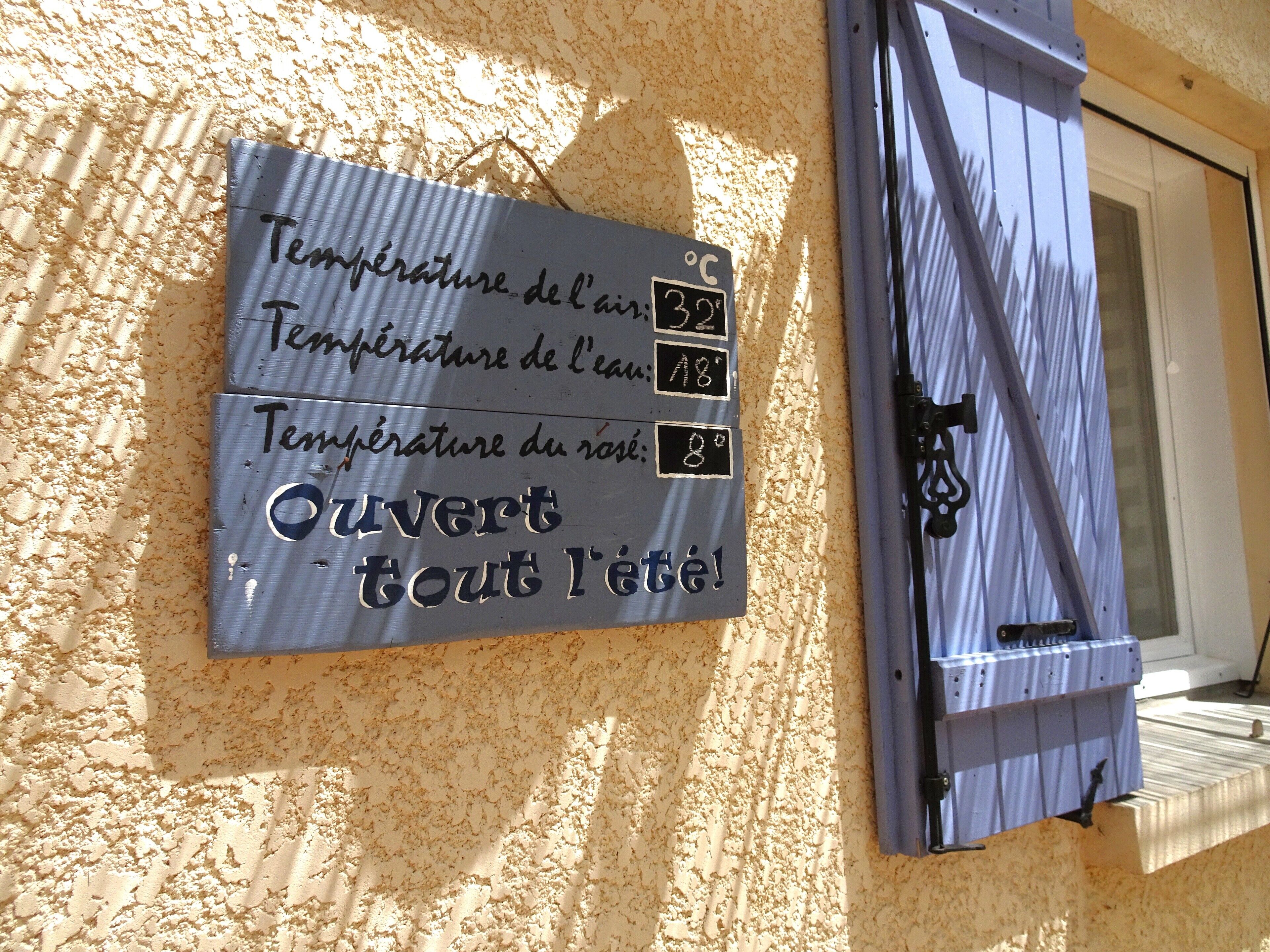 A wall-mounted sign with temperature readings for air, water, and rose.