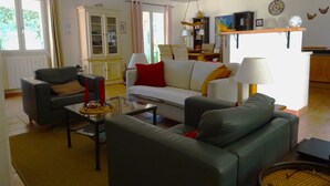 Ein Wohnzimmer mit einer Couch, Sesseln, einem Couchtisch und einem Essbereich mit Tisch und Stühlen.