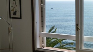 Una habitación con vista al mar, un cuadro abstracto enmarcado y una lámpara de metal.