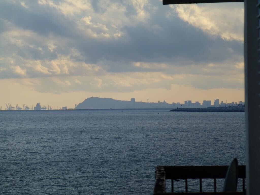 Vista de um corpo d'água com um horizonte urbano distante e uma grande colina ou montanha.