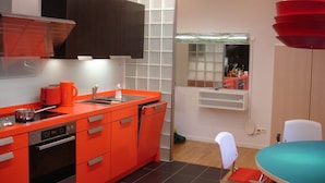 A compact kitchen with orange cabinetry, a built-in oven, and a window with a view. - Luxury apartment in the trendy district of Berlin Mitte (Berlin)