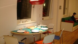 A dining area with a round table set for four, chairs with blue and orange cushions, and a red pendant light above. - Luxury apartment in the trendy district of Berlin Mitte (Berlin)
