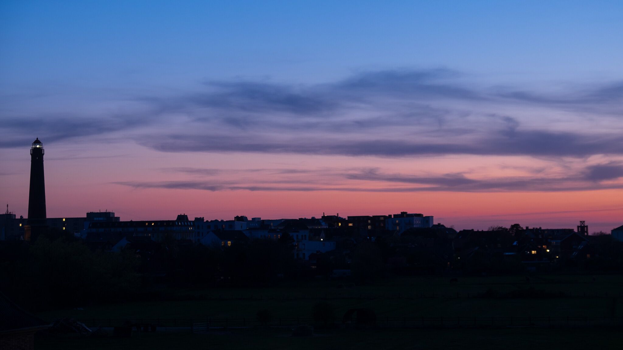 A cityscape at dusk with a prominent tower and residential buildings.