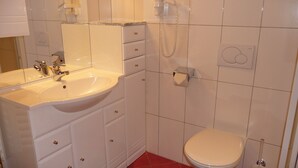 A bathroom with a sink, mirror, toilet, and shower.
