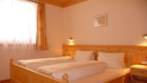 A double wooden bed with two pillows and a nightstand with a lamp.