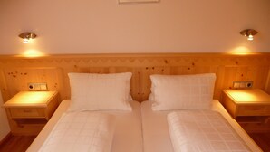 A double bed with a wooden headboard, two bedside tables with lamps, and a small drawer under each table.