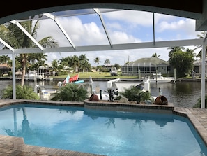 A pool with a view of a marina, palm trees, and a house in the background.
