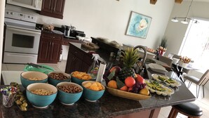Un comptoir de cuisine avec des bols remplis de collations, un ananas et un panier de fruits.