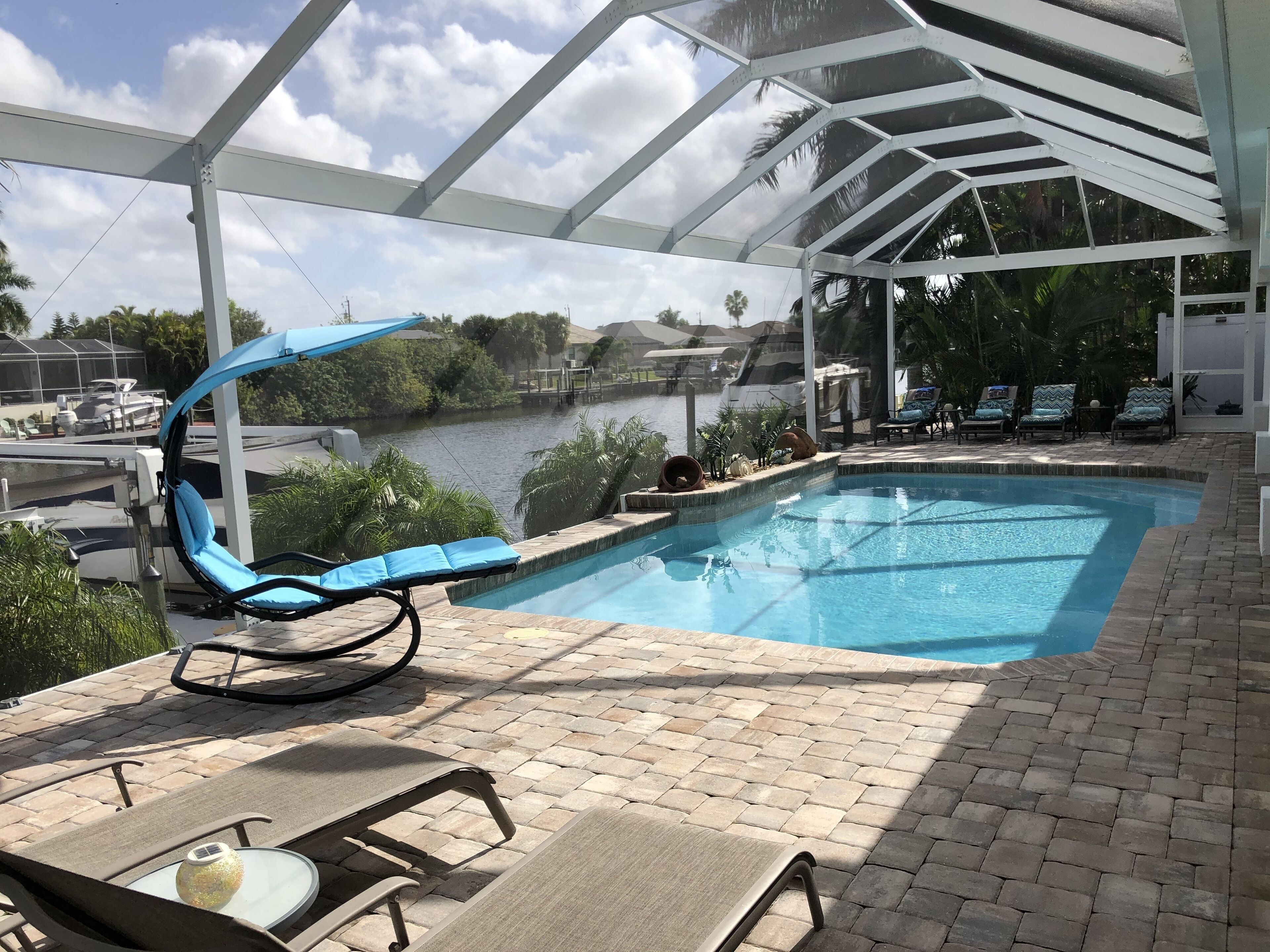 A pool area with lounge chairs and a view of a body of water.