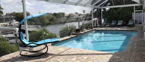 A pool area with lounge chairs and a view of a body of water.