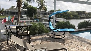 Un espace patio avec une piscine, des chaises longues et une table agrémentée d’un vase.