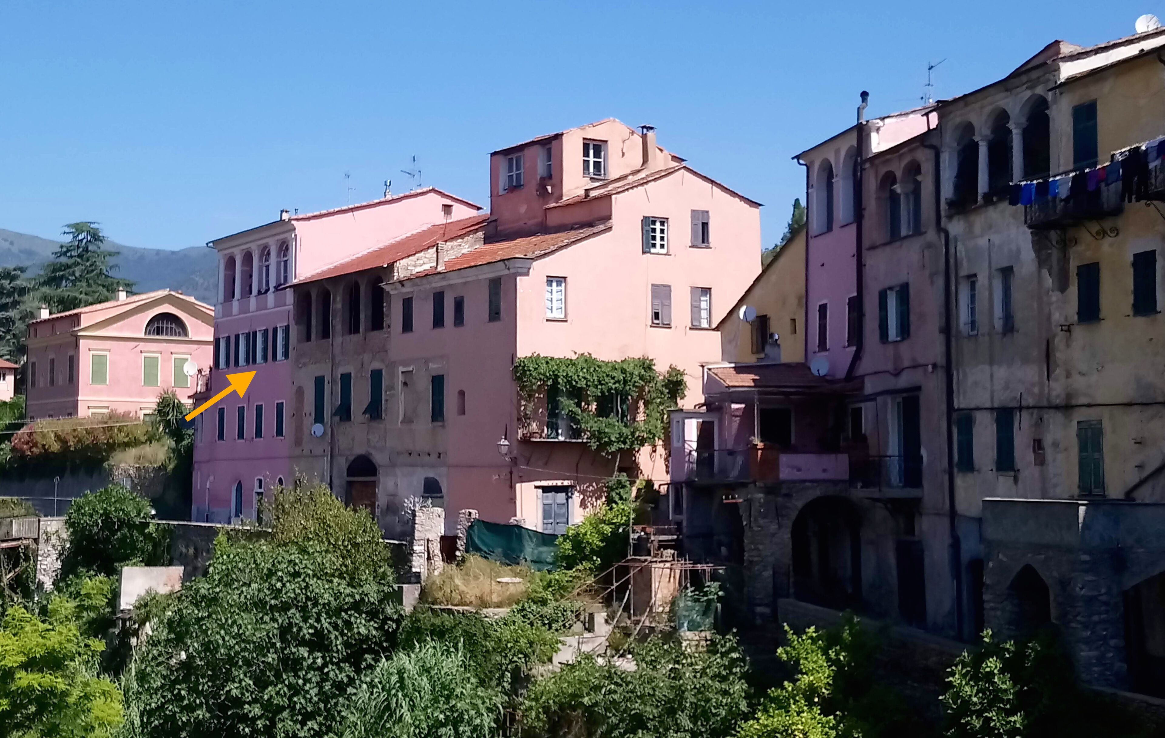 A row of historic buildings with arched windows and balconies, some with laundry hanging out to dry.