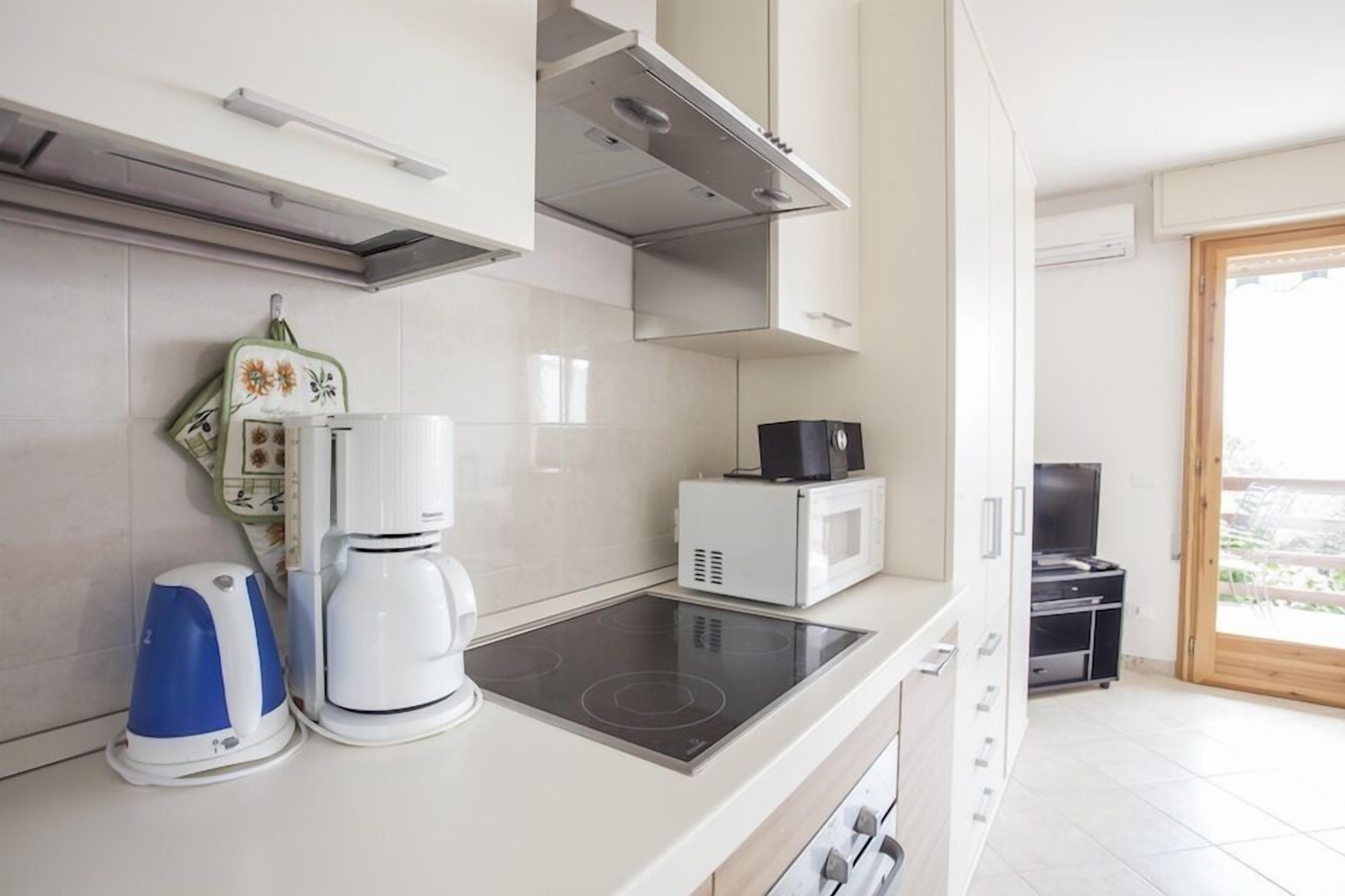 A modern kitchen with a built-in stove, a coffee maker, and a microwave.