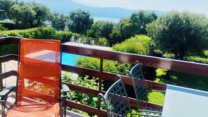 A terrace with a view of a lake and mountains, featuring a table and chairs. - Apartment with air conditioning, sea view, swimming pool, Wi-Fi, quiet hill, parking. (Toscolano Maderno)