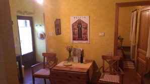 Ein Essbereich mit einem Holztisch und Stühlen, einer Vase mit Blumen und einem Poster an der Wand.