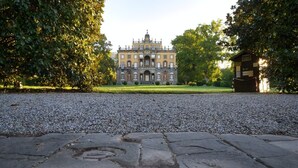 Ein historisches Gebäude mit einer symmetrischen Fassade, einem zentralen Eingang und einem gepflegten Garten.