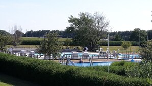 A swimming pool area with multiple pools, lounge chairs, and a large tree in the background. - TOP!!! Headquarters u. quiet location, modern DHH, garden, 5 * level, WiFi, bicycles (Horumersiel)