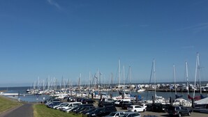 A marina with numerous sailboats docked, a parking area with cars, and a clear blue sky. - TOP!!! Headquarters u. quiet location, modern DHH, garden, 5 * level, WiFi, bicycles (Horumersiel)